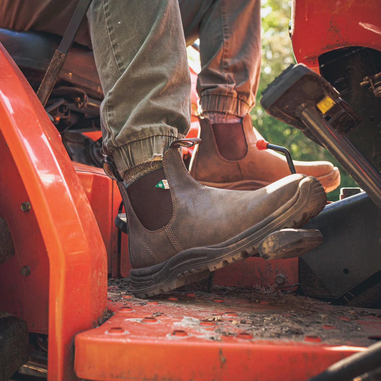Men wearing Blundstone 180 Work Safety Waxy Rustic Brown boots on a red vehicle with a blurred background | shop now on Foot Sensation