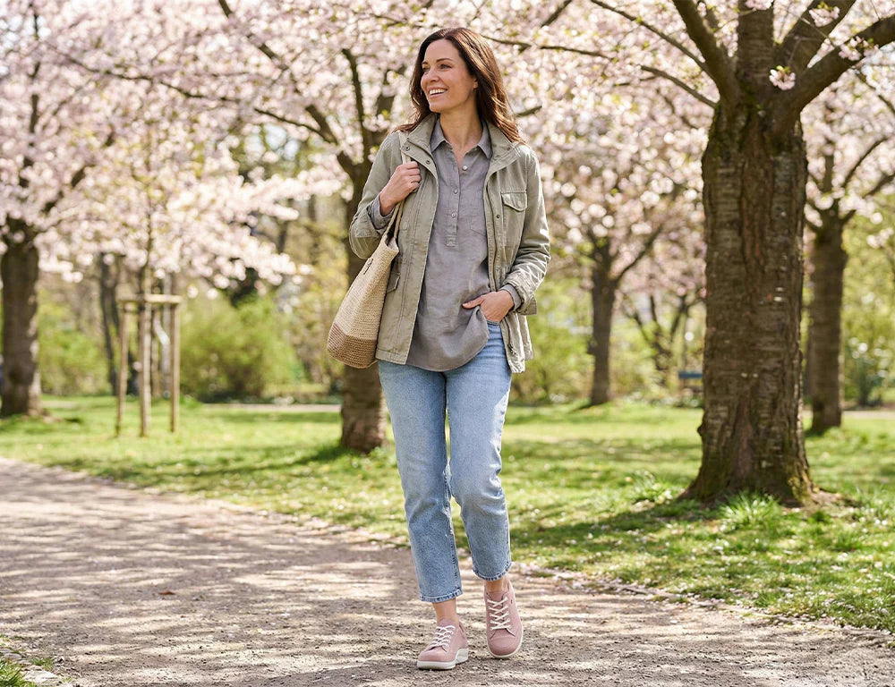 Woman wearing Pink Finn Comfort Womens's sneakers and walking in a park with cherry blossom trees in the background
