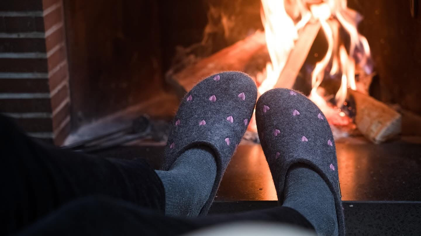 Feet in HAFLINGER CUORICINI SLIPPERS grey gray cozy slippers by a fireplace