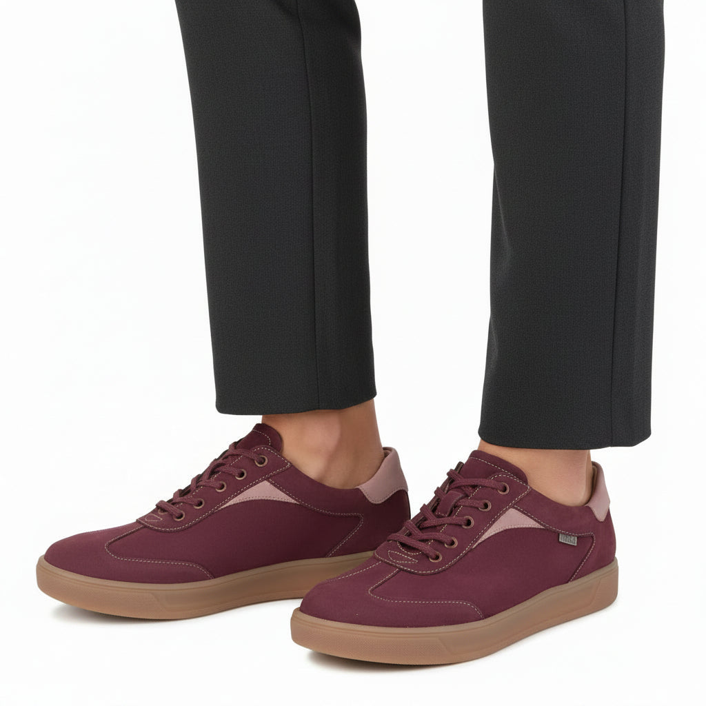 Model with pants wearing pairs of FINN COMFORT Interlagos leather Sneaker color rumba candy cherrry, comfortable removable leather-covered cork footbed supports orthopedic insoles in white background.